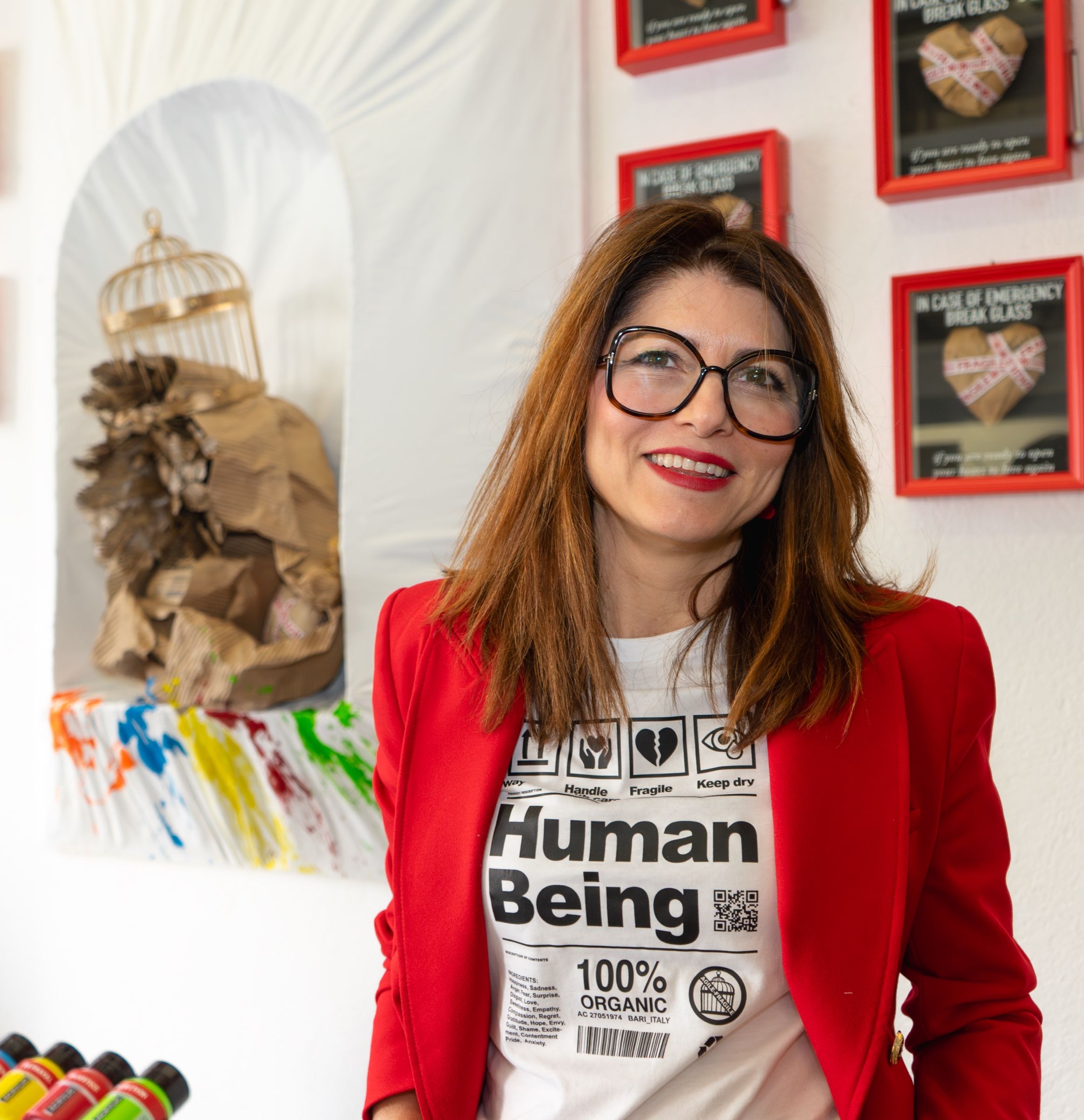 The artist in a red jacket and a Human Being T-shirt in front of the wall of red frames.