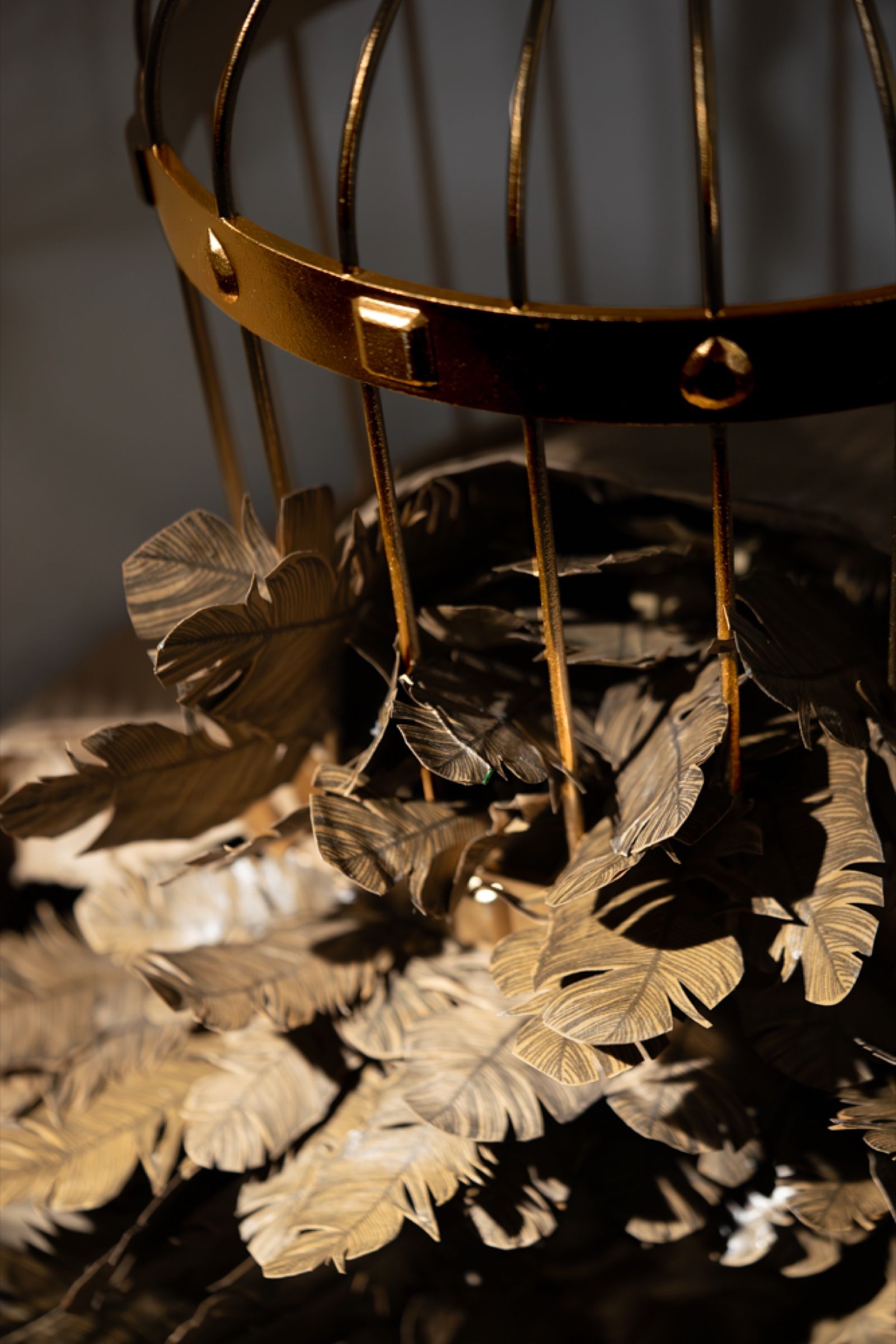 A golden cage surrounded by hand-cut paper feathers.