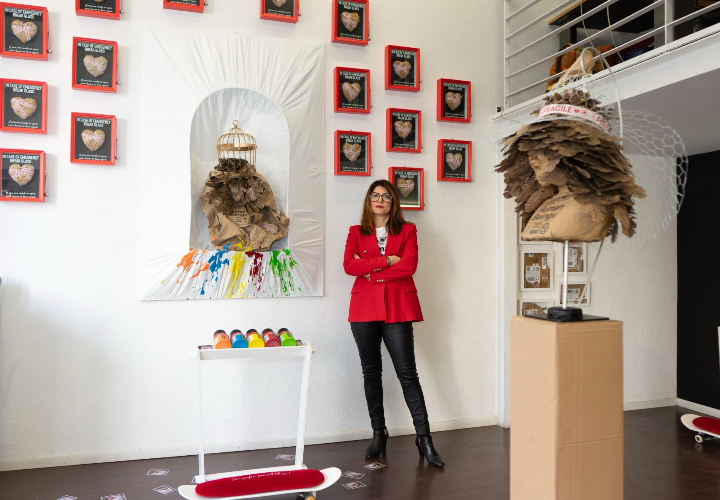 The full installation in a white room, with red frames on the walls and the artist standing.